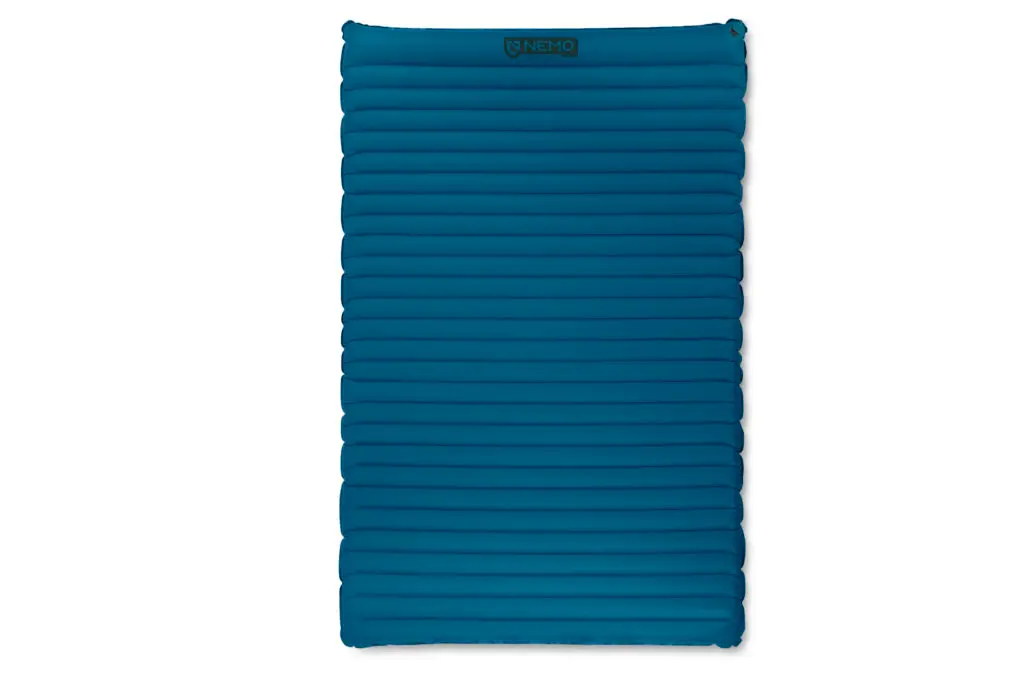Un matelas de couchage gonflable rectangulaire bleu foncé avec des chambres à air horizontales et des coins arrondis, présenté sur un fond blanc.
