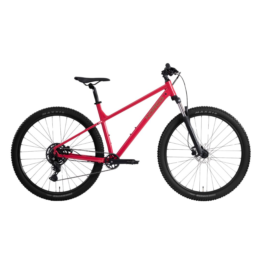 Un vélo de montagne rouge avec une selle, un guidon et des pneus noirs, doté d'une fourche à suspension avant et de freins à disque, présenté sur un fond blanc.