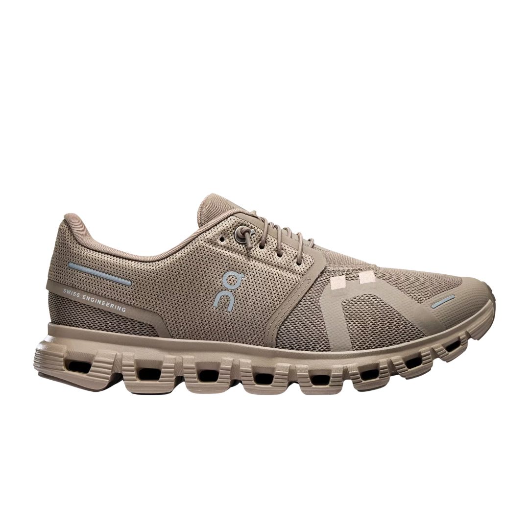 La CHAUSSURE URBAIN ON CLOUD 6 POUR FEMME est une chaussure de sport beige avec une matière en maille, une fermeture à lacets, une semelle segmentée et des logos de marque subtils avec des accents bleu clair et beige.