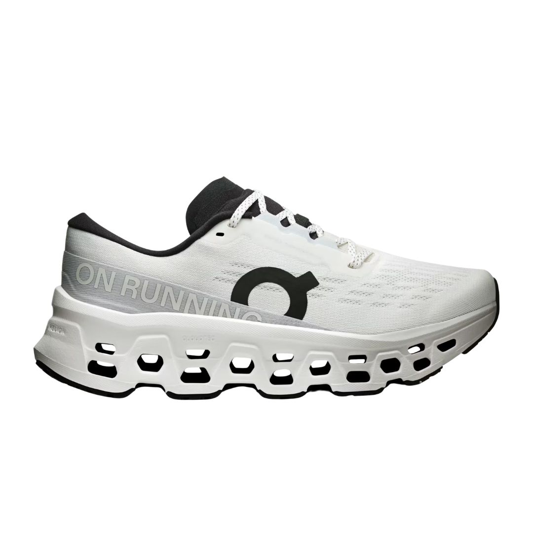 La CLOUDMONSTER 3 W est une chaussure de course blanche et noire avec une semelle découpée unique, affichant le nom de la marque ON RUNNING et un logo "O" noir sur le côté.