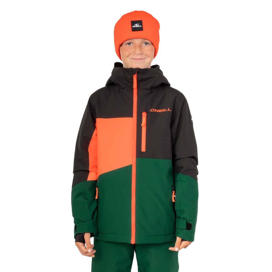 Un garçon porte la MANTEAU DE SKI O'NEILL FWC CRUZ TRIPLE, une veste d'hiver colorée en noir, orange et vert, ainsi qu'un bonnet orange. Il se tient debout et sourit à la caméra.