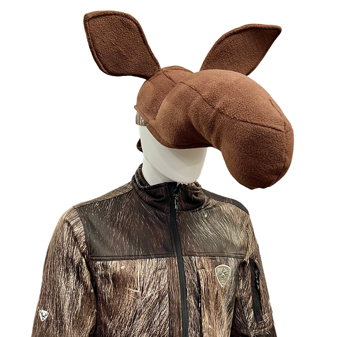 Un mannequin porte un bonnet en polaire marron en forme de tête d'élan avec de grandes oreilles et un museau, ainsi qu'une veste à motifs de camouflage.