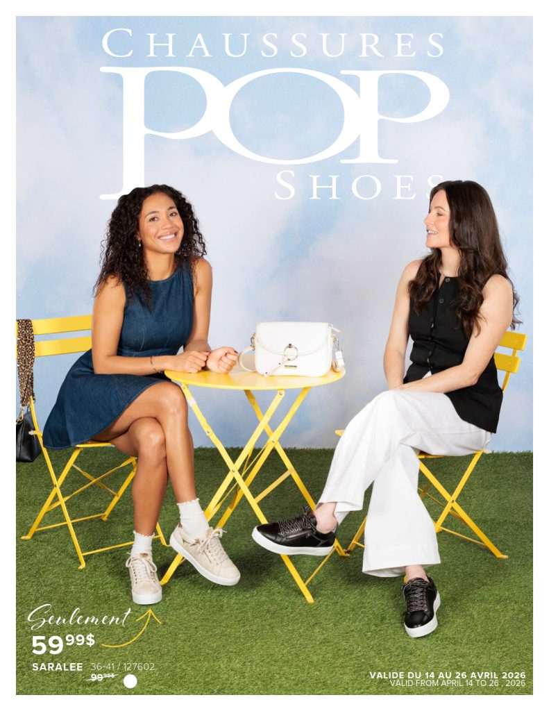 Deux femmes sont assises à une table jaune sur du gazon artificiel et se sourient. L'une porte une robe bleue et des baskets, l'autre un haut noir, un pantalon blanc et des chaussures noires. Un sac à main blanc est posé sur la table. En arrière-plan, on peut lire "Chaussures Pop Shoes".