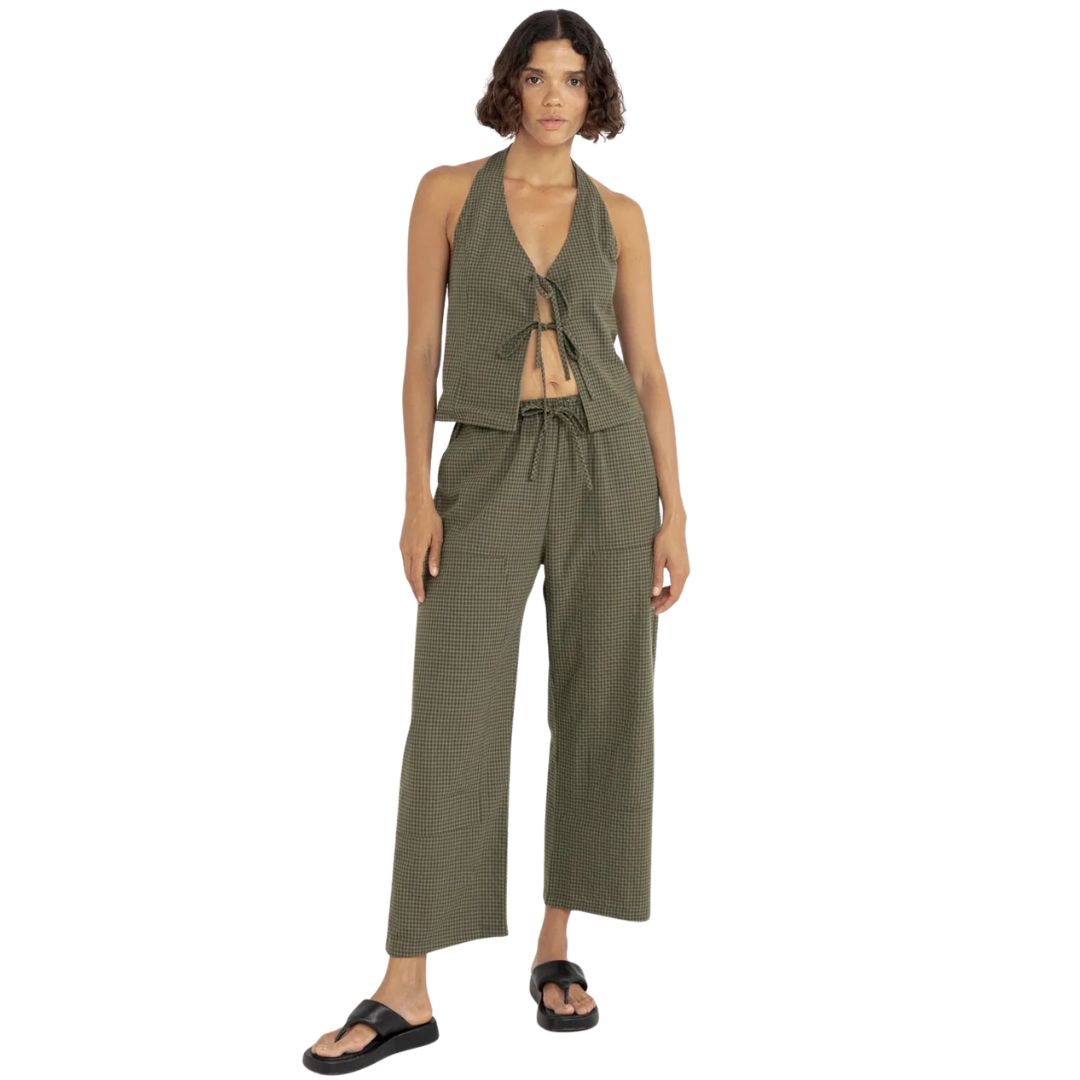 Une personne portant un pantalon vert olive à carreaux LOUISE CHECK DRAWSTRING PANT, un dos nu assorti et des sandales noires, debout sur un fond blanc.