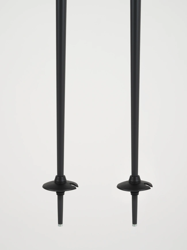 Deux bâtons de ski noirs sont alignés verticalement avec des poignées et des paniers simples, sur un fond blanc uni.
