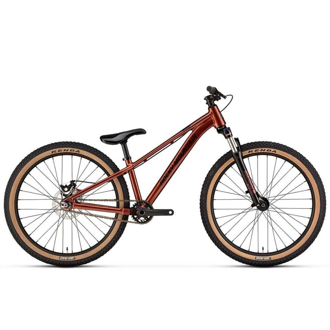 Le VÉLO DE MONTAGNE ROCKY MOUNTAIN FLOW 24" POUR JUNIOR est représenté de profil sur fond blanc, avec un cadre marron, des pneus à bords marron, une selle noire et une suspension avant.