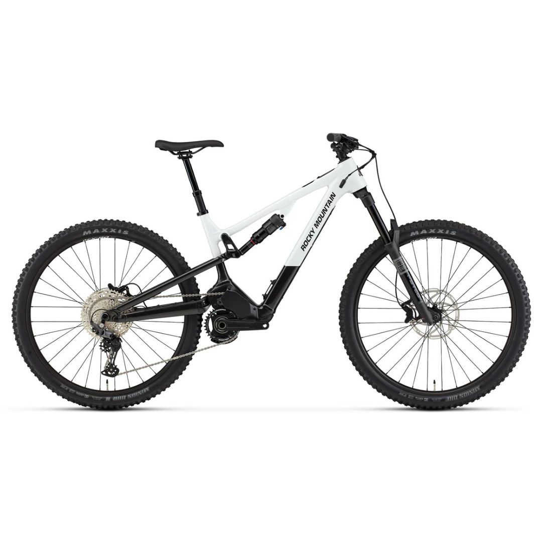 Le VÉLO DE MONTAGNE ÉLECTRIQUE ROCKY MOUNTAIN INSTINCT POWERPLAY SL A30 est doté d'un cadre blanc et noir, de pneus épais, d'une suspension avant et arrière et d'un moteur à entraînement central. Il est représenté en vue latérale sur fond blanc.