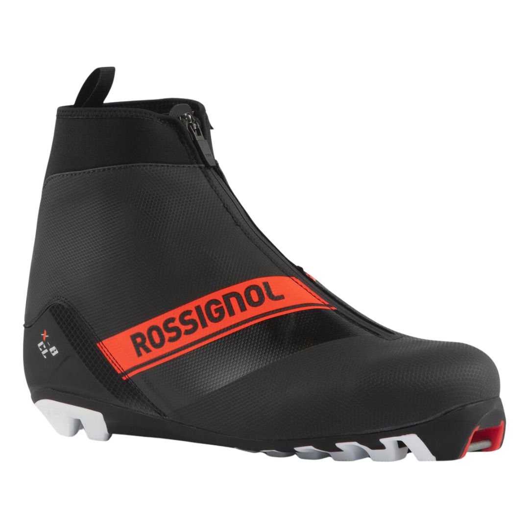 La X-8 CLASSIC est une chaussure de ski de fond Rossignol noire et rouge avec une fermeture éclair, une semelle robuste et une bande rouge audacieuse avec le logo Rossignol.