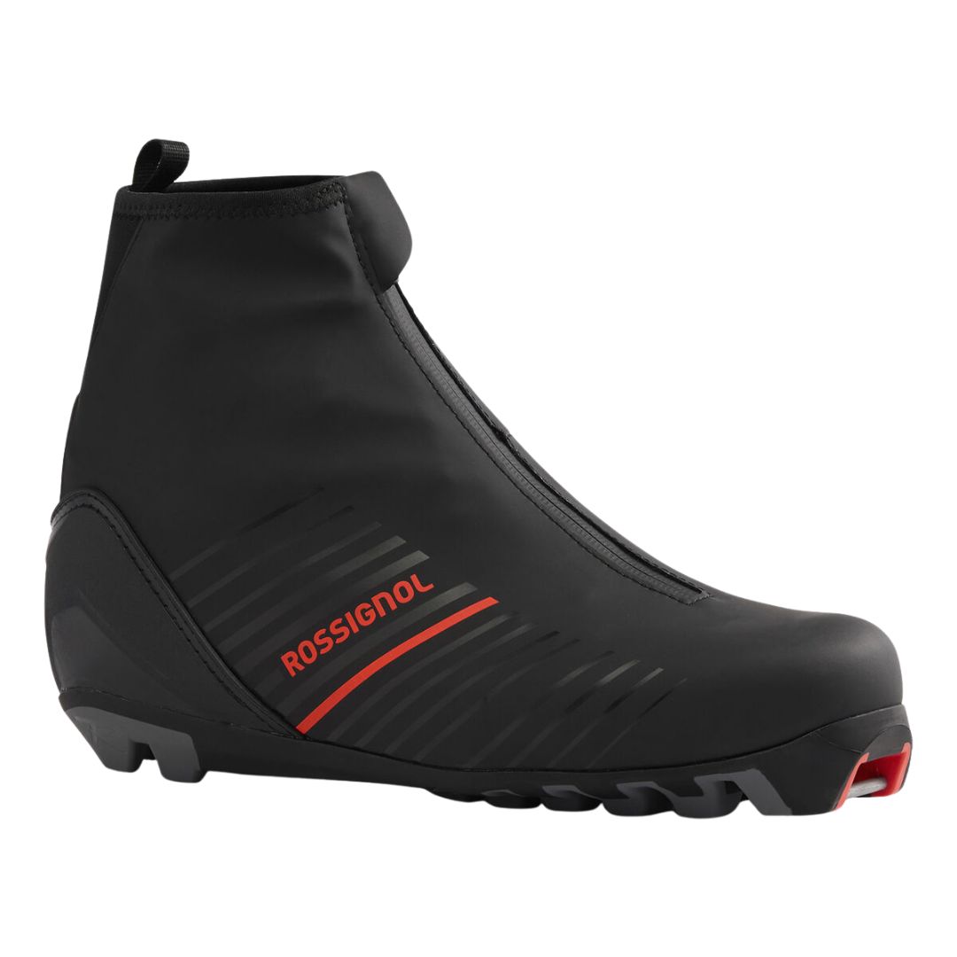 La BOTTE DE SKI DE FOND ROSSIGNOL X-7 CLASSIC est une chaussure de ski de fond noire avec des accents rouges, une fermeture éclair à l'avant et une semelle robuste conçue pour les fixations.