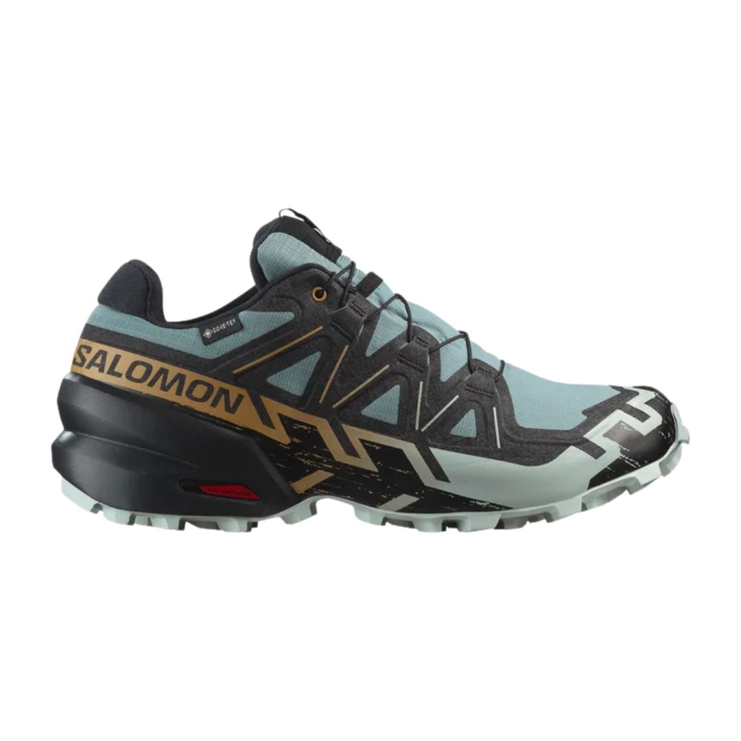 Une chaussure de trail Salomon bleu clair et noir avec des accents dorés, avec une semelle robuste, des motifs géométriques et une marque proéminente sur le côté.