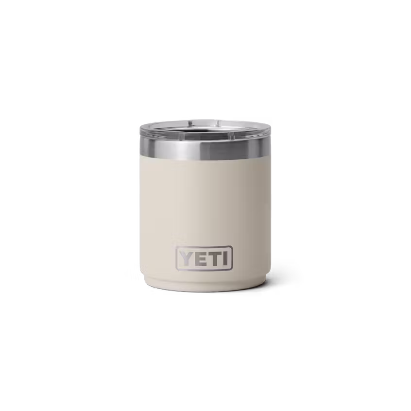 Un gobelet isotherme RAMBLER 10 OZ LOWBALL 2.0 beige avec un bord et un couvercle en acier inoxydable, présenté sur un fond blanc uni.