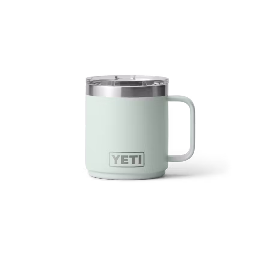 Un RAMBLER 10 OZ MUG MS vert menthe clair avec une poignée et un couvercle en acier inoxydable est représenté sur un fond blanc uni, avec le logo Yeti sur le devant.