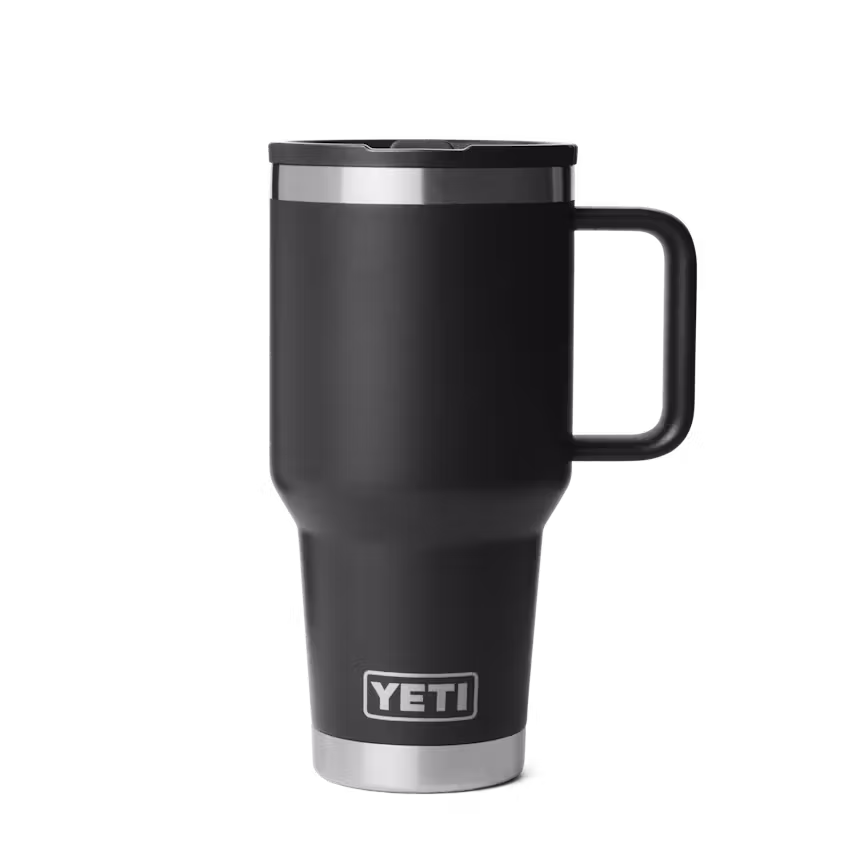 Le RAMBLER 30 OZ TRAVEL STR MUG noir, avec une poignée et un bord en acier inoxydable, affiche le logo YETI près de la base et se détache sur un fond blanc uni.