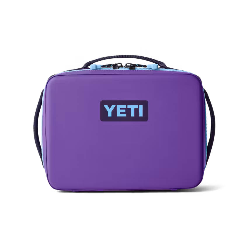 Une boîte-repas DAYTRIP INSUL 5 L de la marque Yeti, de couleur violette, dotée d'une poignée noire et d'une fermeture éclair bleu clair, avec le logo YETI en noir et bleu sur le devant, sur fond blanc uni.
