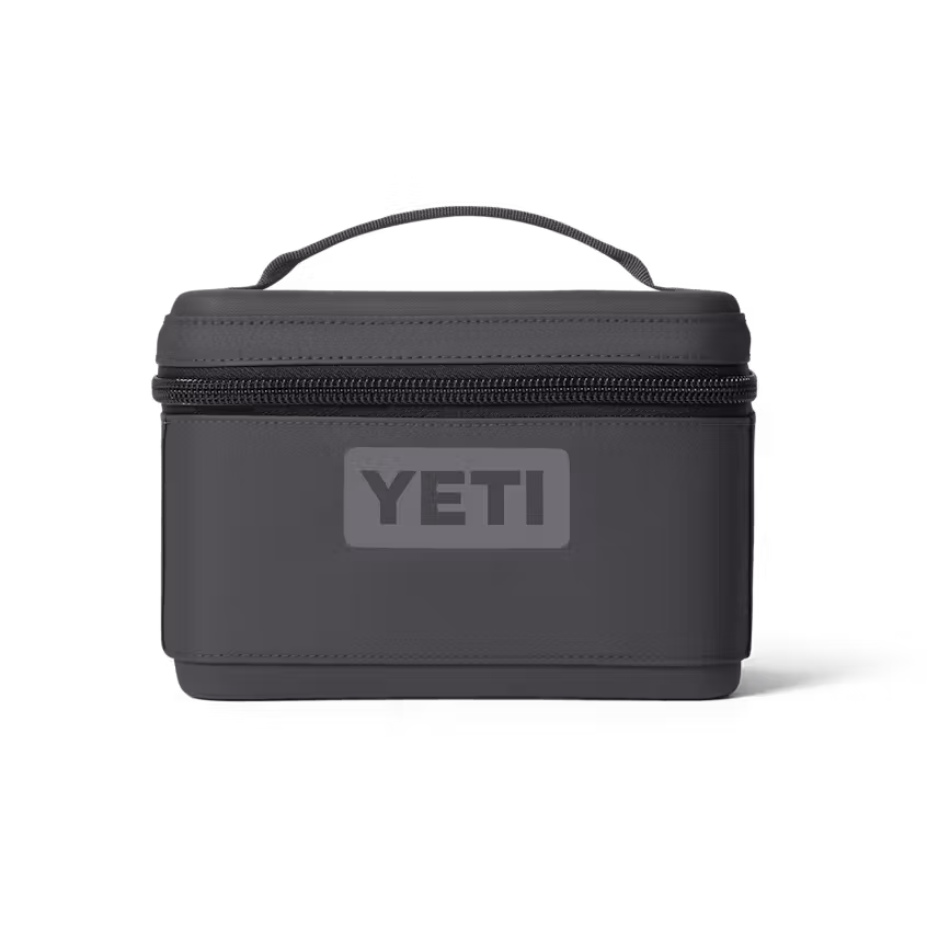 Une boîte à goûter DAYTRIP 3L INSUL SNACK BOX de YETI, compacte, rectangulaire et de couleur gris foncé, dotée d'une fermeture à glissière et d'une poignée sur le dessus, présentée sur fond blanc.