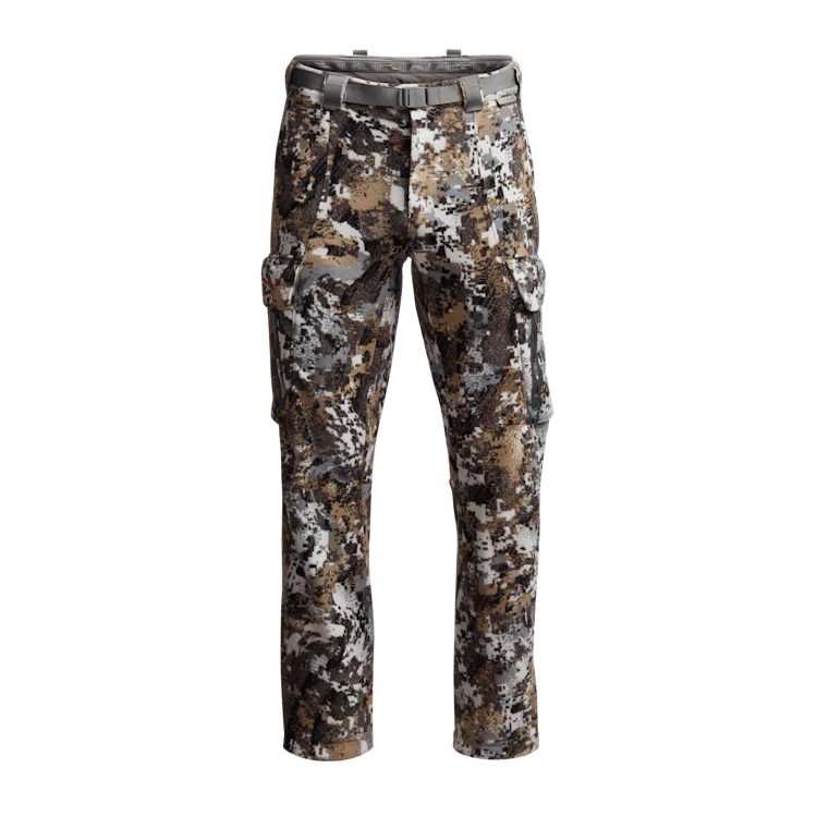 Pantalon de chasse camouflage aux motifs variés de vert, marron, noir et blanc, avec plusieurs poches et une ceinture grise à la taille. Le pantalon est présenté sur un fond blanc uni.