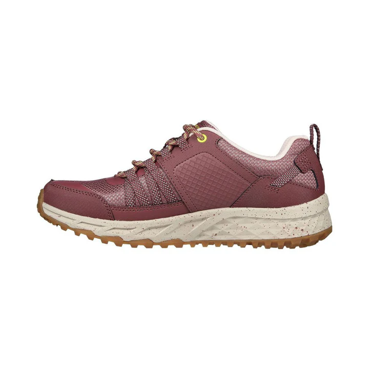 Une chaussure de sport marron avec un design texturé et une semelle coussinée beige. La chaussure est dotée de lacets marron avec une touche jaune près de l'œillet supérieur, d'un motif de bande de roulement robuste sur la semelle extérieure et d'un petit emblème noir sur le talon.