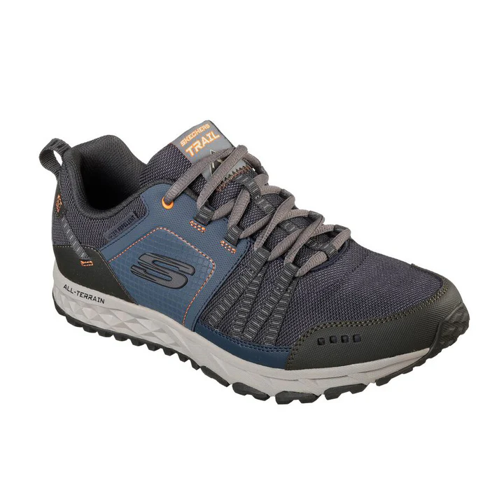 Une chaussure de trail athlétique grise et bleue conçue pour les terrains accidentés, avec des lacets robustes et des semelles texturées pour une meilleure adhérence. La chaussure présente un logo « S » sur le côté, des accents orange et les mots « All-Terrain » et « Trail » sont visibles sur la chaussure.