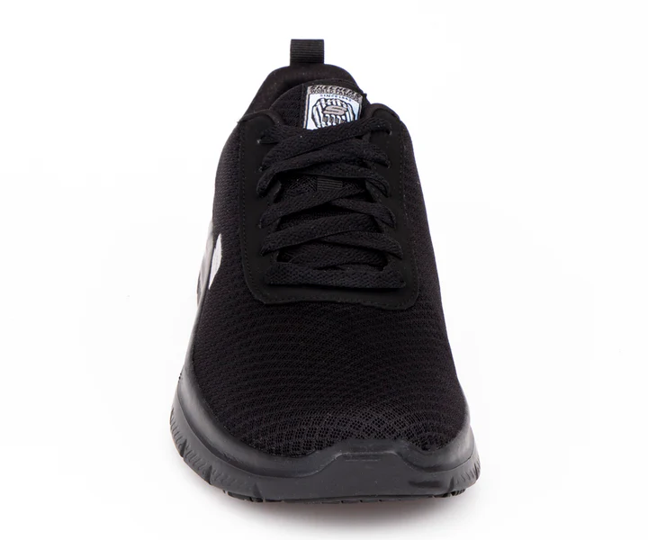 Vue de face d'une chaussure de sport noire avec tige en mesh et lacets noirs sur fond blanc. La chaussure arbore une étiquette de marque sur la languette et un design épuré.