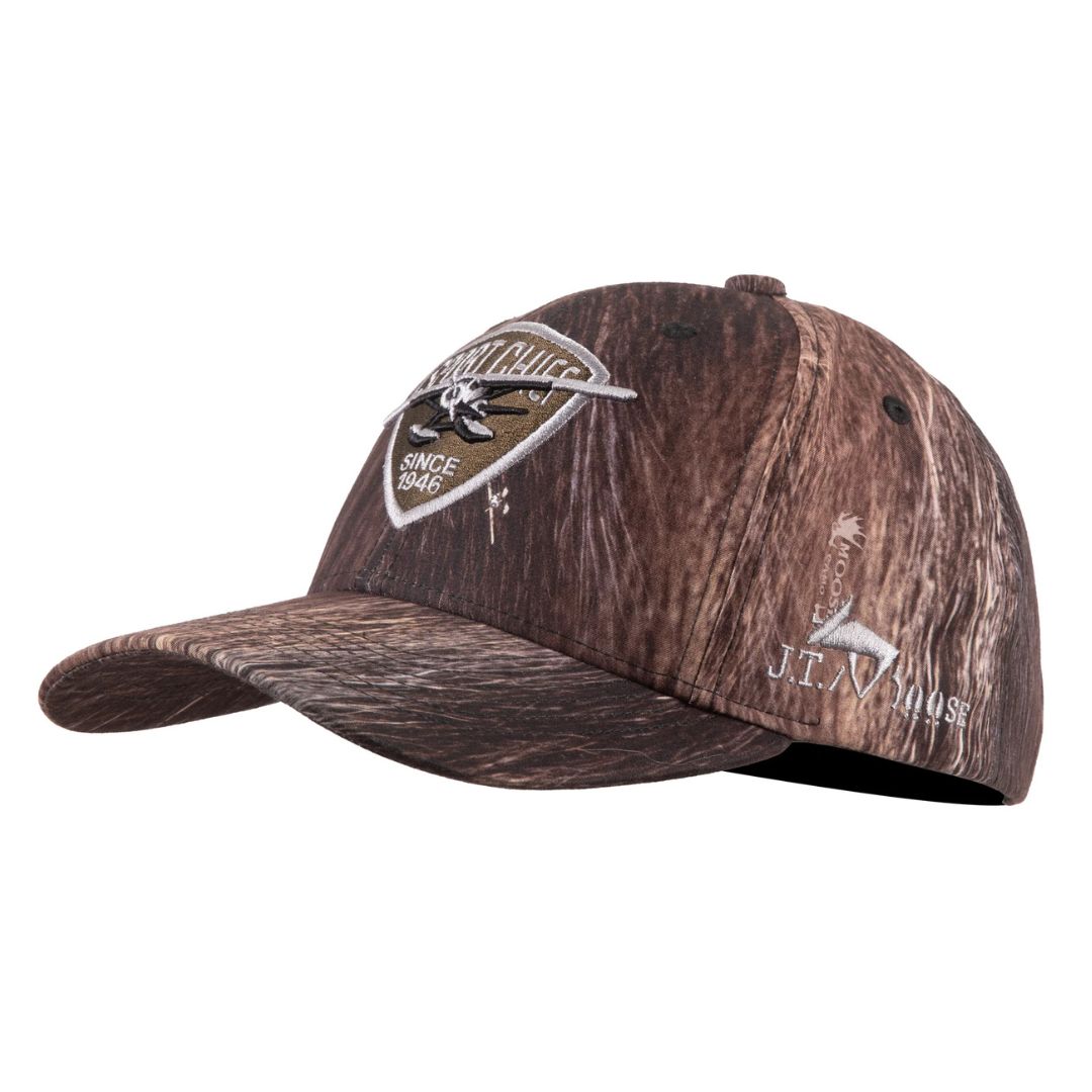 Casquette de base-ball marron camouflage à bord incurvé, avec des écussons et des logos brodés sur le devant et le côté. L'écusson principal représente un oiseau et un texte indiquant "Since 1946".