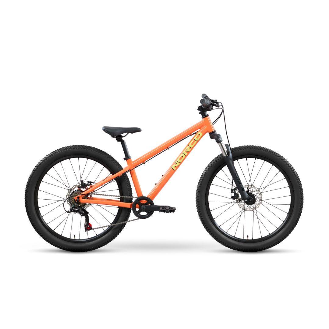 Un vélo tout-terrain Norco STORM S24 PEACH est représenté de profil sur fond blanc, avec un guidon, une selle et des pneus noirs. Il est équipé d'une suspension avant et de freins à disque.