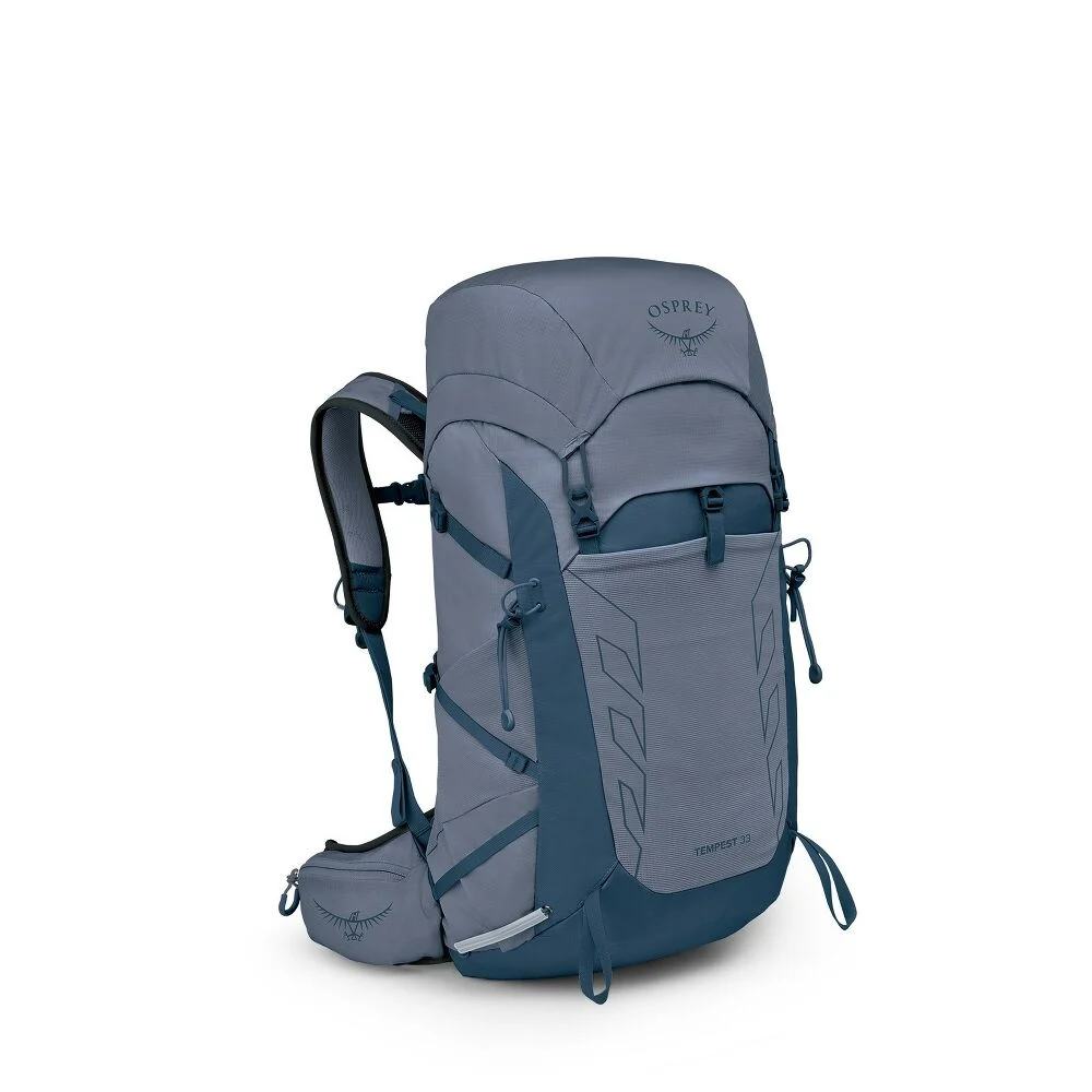 Un sac à dos de randonnée SAC DE RANDONNÉE OSPREY TEMPEST 33, bleu et gris, avec des compartiments à fermeture éclair, des bretelles réglables, des poches latérales et une ceinture rembourrée, se tient debout sur un fond blanc uni.