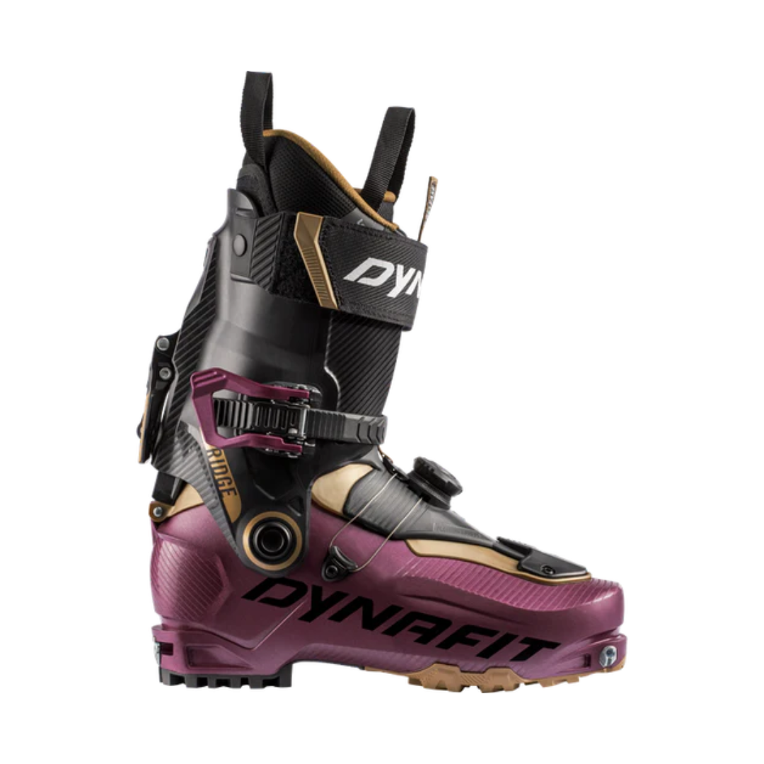 La vue latérale d'une RIDGE W révèle une chaussure de ski Dynafit violette et noire avec des accents métalliques. Elle est dotée de plusieurs boucles, d'un design élégant pour la randonnée alpine et d'une semelle axée sur la traction.