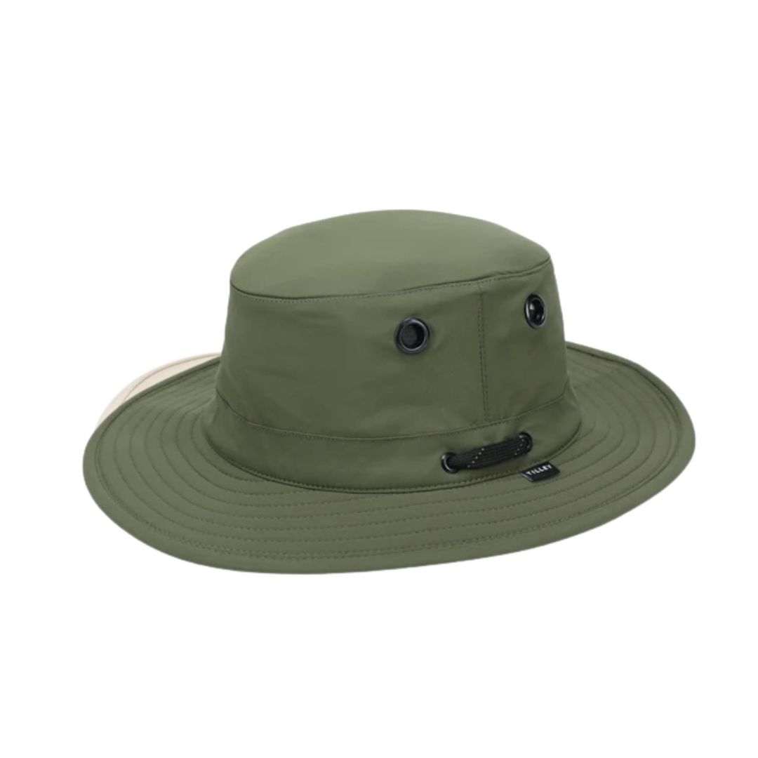 L'ULTRALIGHT T5 CLASSIC est un chapeau baquet à large bord vert olive avec deux œillets d'aération noirs par côté, une petite étiquette noire sur le devant, un bord légèrement incurvé et une construction en tissu léger.