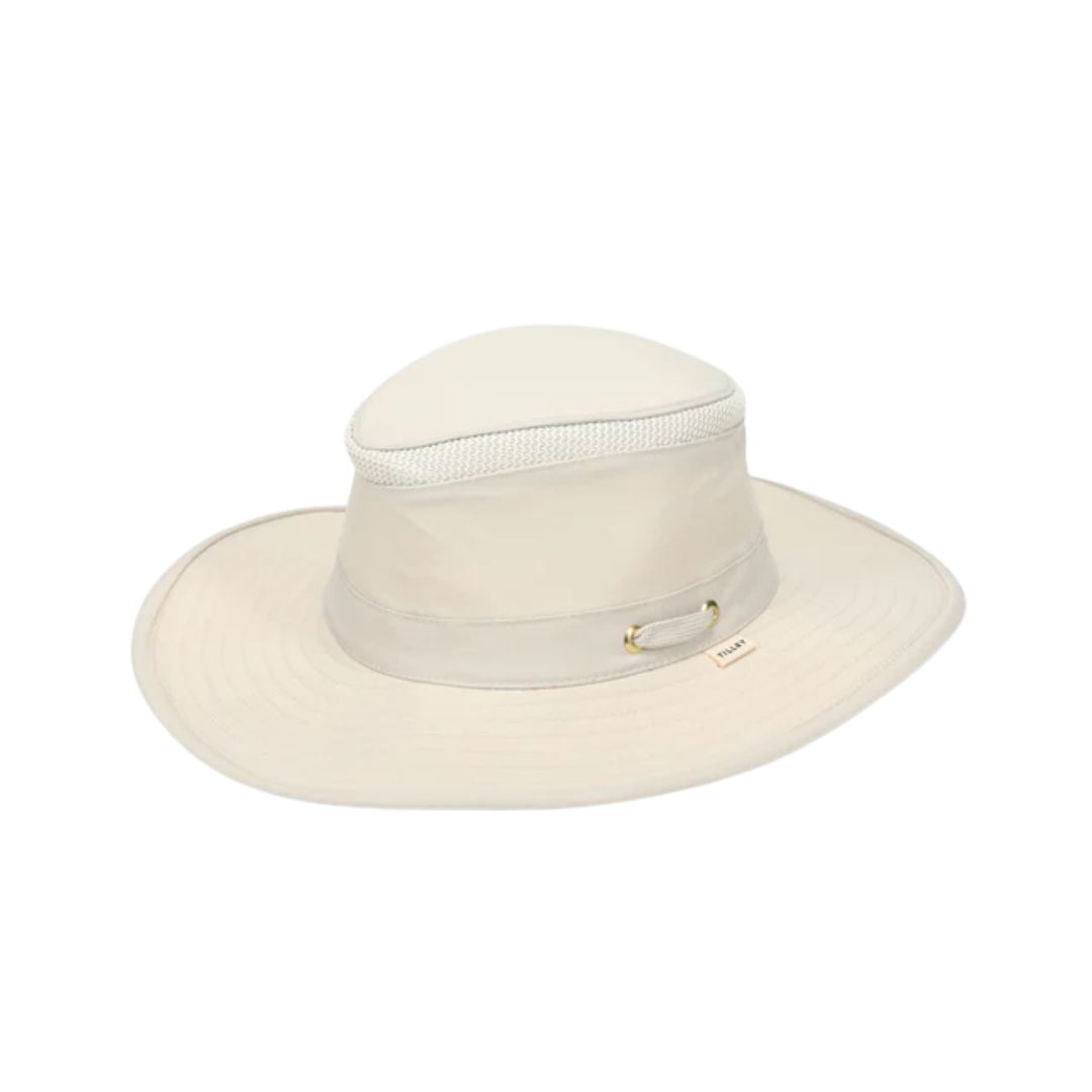 L'AIRFLO BROAD BRIM est un chapeau de soleil beige clair à large bord, doté d'un panneau en maille autour de la couronne et d'œillets métalliques sur le côté, sur fond blanc.