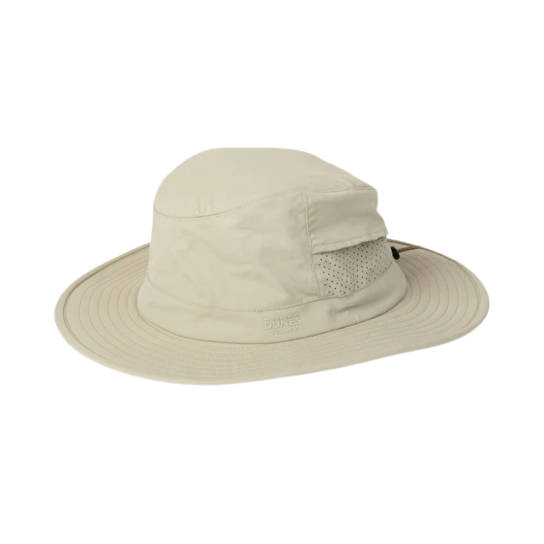 Le CHAPEAU D'AVENTURE TILLEY DUNES EXPLORER est un chapeau de soleil beige clair à large bord, doté de panneaux d'aération latéraux en maille, idéal pour une utilisation en extérieur.