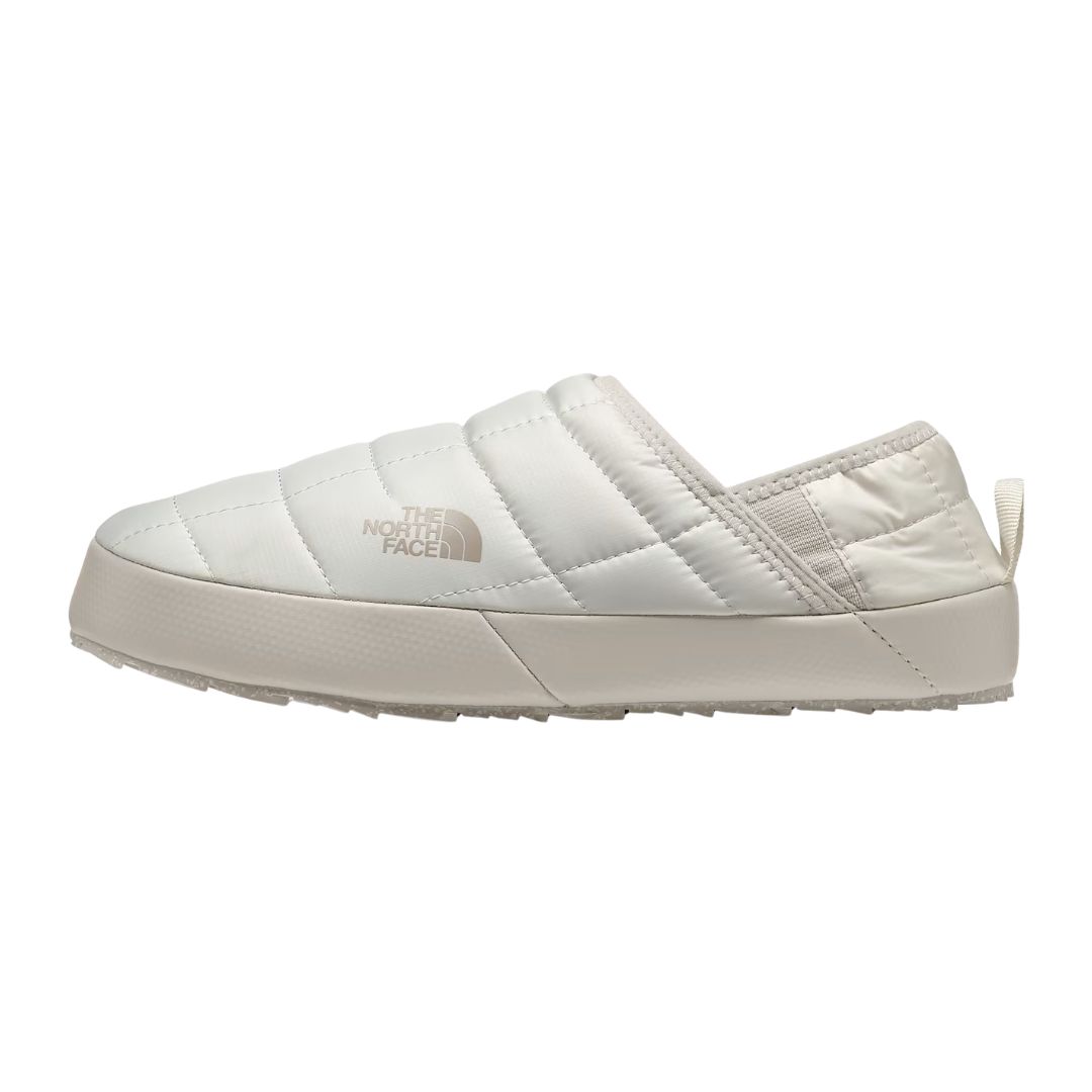 Vue de profil du modèle FEM, une chaussure blanche matelassée sans lacets de la marque The North Face, dotée d'une semelle plate et d'une languette au talon.