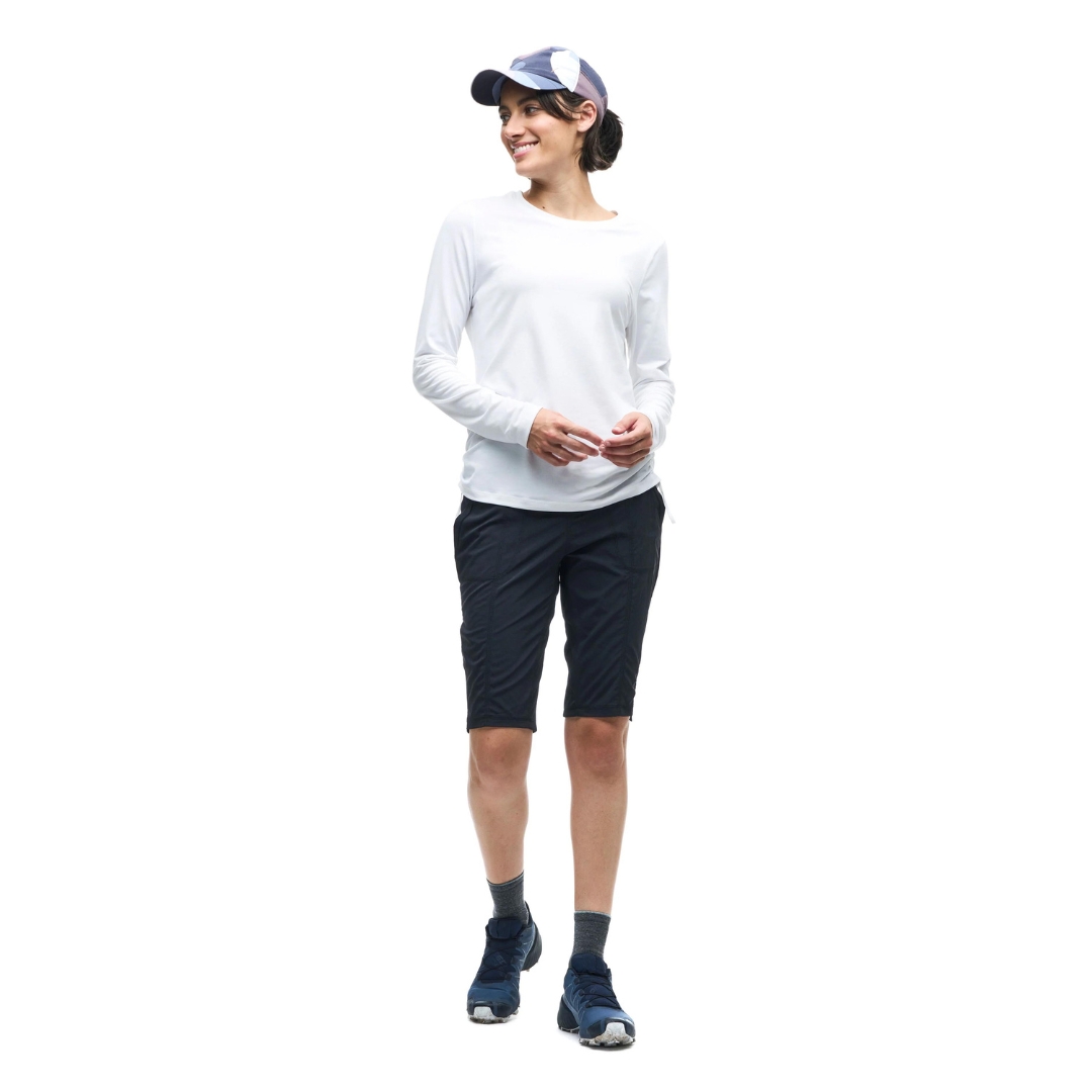 Femme debout avec shorts noir, chandail blanc et casquette