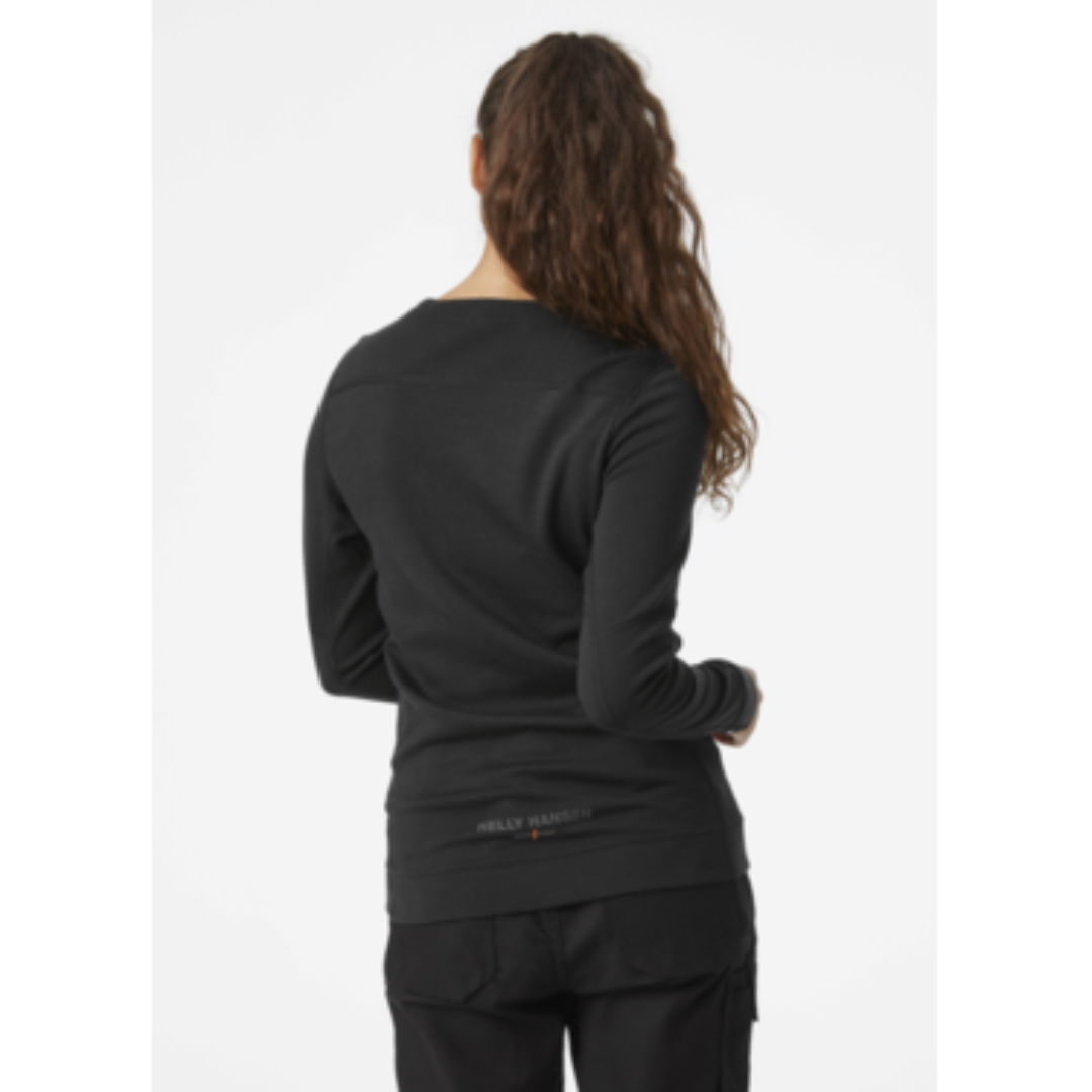 HAUT COUCHE DE BASE EN MÉRINO HELLY HANSEN WORKWEAR LIFA À COL ROND POUR FEMME COULEUR BLACK PORTÉ PAR UNE FEMME VUE DE DOS CHANDAIL NOIR À MANCHES LONGUES NOM HELLY HANSEN WORKWEAR VISIBLE SUR LE BAS CENTRAIL DU CHANDAIL