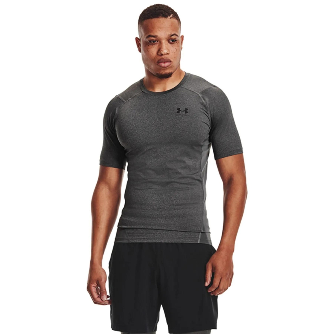 t-shirt AJUSTÉ UNDER ARMOUR HEATGEAR ARMOUR POUR HOMME couleur 090-CARBON HEATHER-BLACK porté par un homme vu de face avec le chandail gris à manches courteavec le nom et logo under armour imprimé en noir à la poitrine gauche