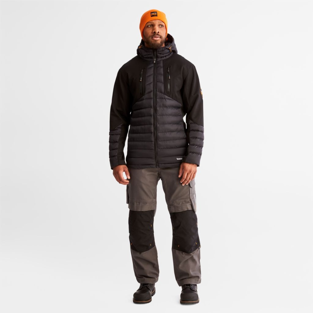 PANTALON DE TRAVAIL TIMBERLAND PRO IRONHIDE FLEX À GENOULLIÈRES POUR HOMME couleur gunmetal porté par un homme vu de la tête aux pieds, l'homme est habiller pour l'extérieur avec le pantalon gris avec genoux renforcés nois