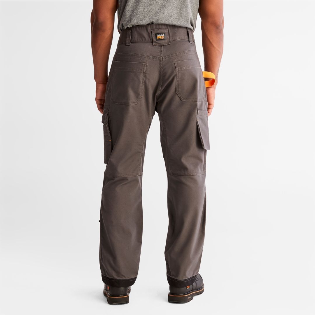 PANTALON DE TRAVAIL TIMBERLAND PRO IRONHIDE FLEX À GENOULLIÈRES POUR HOMME couleur gunmetal porté par un homme vu de dos de la taille aux pieds, large passant à ceinture arrière orné d'un écusson Timberland Pro visible
