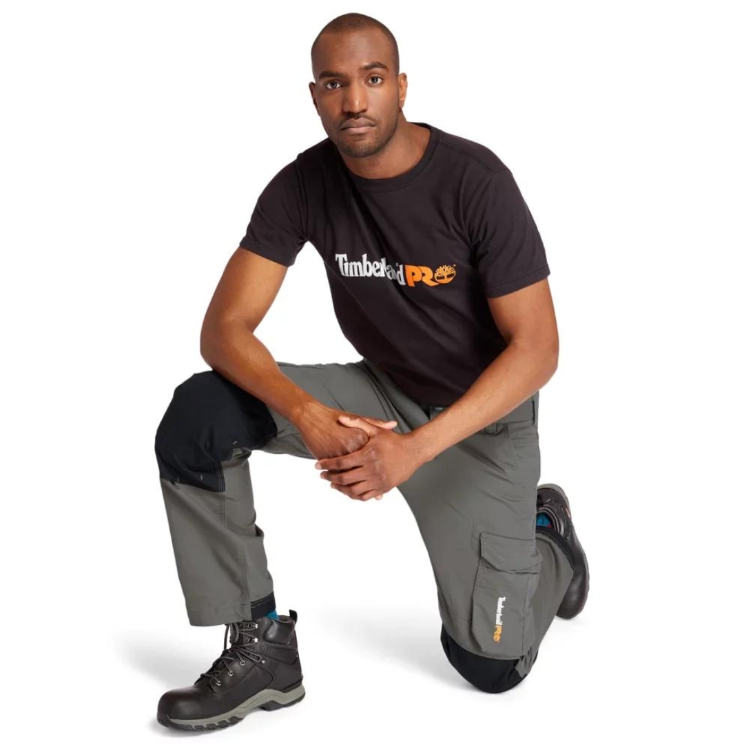 PANTALON DE TRAVAIL TIMBERLAND PRO IRONHIDE FLEX À GENOULLIÈRES POUR HOMME couleur gunmetal porté par un homme accroupi qui montre la flexibilité du pantalon gris acier