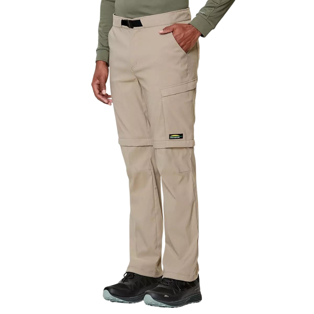 PANTALON DE PLEIN AIR CONVERTIBLE CHLOROPHYLLE RAID POUR HOMME COULEUR ÉRABLE PORTÉ PAR UN HOMME VU DE FACE DE LA TAILLE AUX PIEDS AVEC LE PANTALON BEIGE PALE CEINTURE ET BOUCLE VISIBLE AU HAUT DU PANTALON L'HOMME A UNE MAIN DANS LA POCHE LATÉRALE LOGO CHLOROPHYLLE VISIBLE SUR LA CUISSE GAUCHE