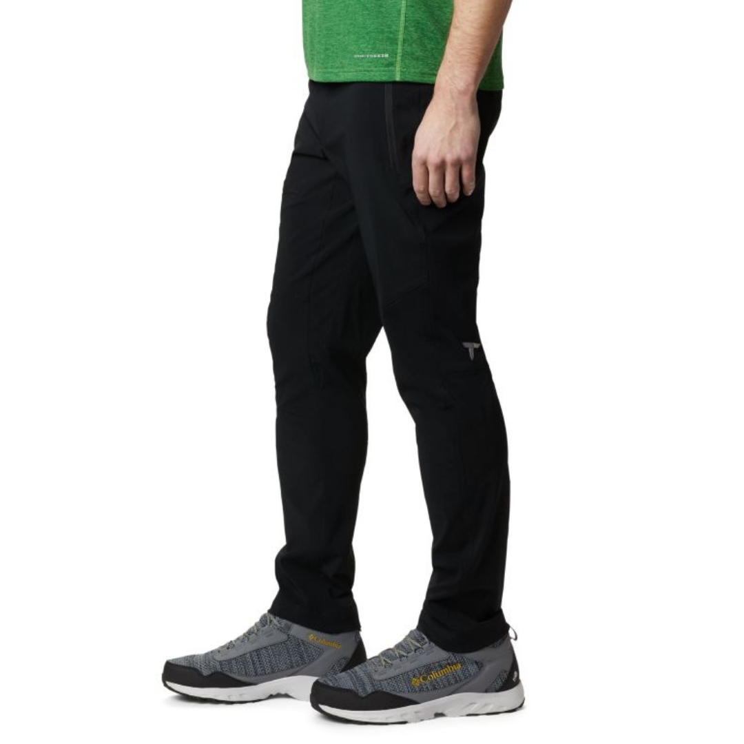 PANTALON DE PLEIN AIR COLUMBIA TITAN PASS POUR HOMME couleur black porté par un homme vu de profil gauche on voit la fermeture éclair de la poche latérale du pantalon entièrement noir
