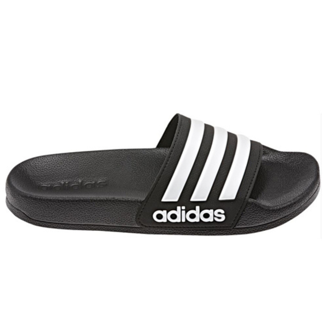 SANDALE ADIDAS ADILETTE SHOWER POUR JUNIOR couleur noir/blanc vue de la sandale droite de profil droit, sandales avec les 3 bandes blanches emblématique ainsi que le nom Adidas en blanc sur le coté de la semelle d'usure, semelle intérieure et d'usure de couleur noire