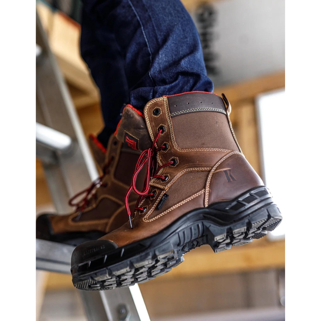 BOTTE DE SÉCURITÉ KINGTREADS WINNIPEG 8″ CSA POUR HOMME couleur brun porté par un homme qui est monté dans un escabeau on voit les crampons de la semelle d'usure de la botte brune