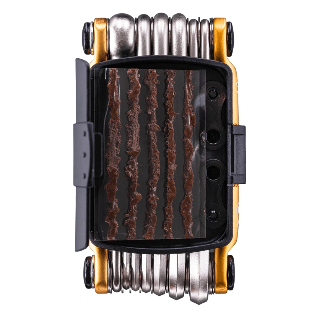 MULTI OUTIL CRANKBROTHERS M13 couleur gold vue de l'outil avec son boitier de plastique noir ouvert laissant voir les bouchons de pneus, et les mailles de chaine (non comprise) rangées à l'endroit réservé à cette fin, clés couleur acier métallique et côtés doré métalliques