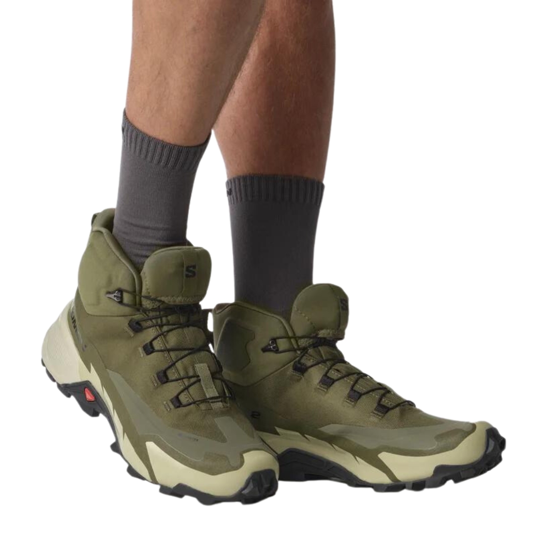 BOTTE DE RANDONNÉE SALOMON CROSS HIKE MID GORE-TEX 2 POUR HOMME couleur Olive Night / Moss Gray / Black vue de la botte droite de couleur vert olive et verte pale et noire porté par un homme vu de biais avant