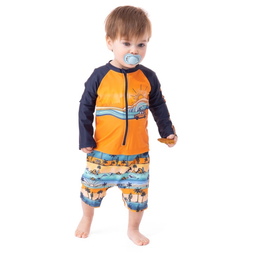 MAILLOT DERMOPROTECTEUR UNE-PIÈCE À MANCHES LONGUES NANÖ POUR GARÇON (2 À 4) couleur jaune vu du maillot jaune orange, marine et bleu à motif bord de mer porté par un garçonet