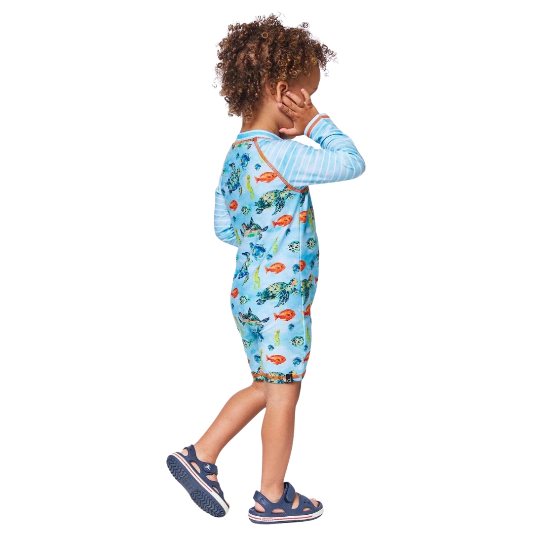 MAILLOT DE BAIN UNE PIÈCE DEUX PAR DEUX RASHGUARD MANCHES LONGUES POUR BÉBÉ GARÇON couleur fish vu du maillot bleu ciel à imprimé tortue/poisson porté par un petit garçon vu de profil droit