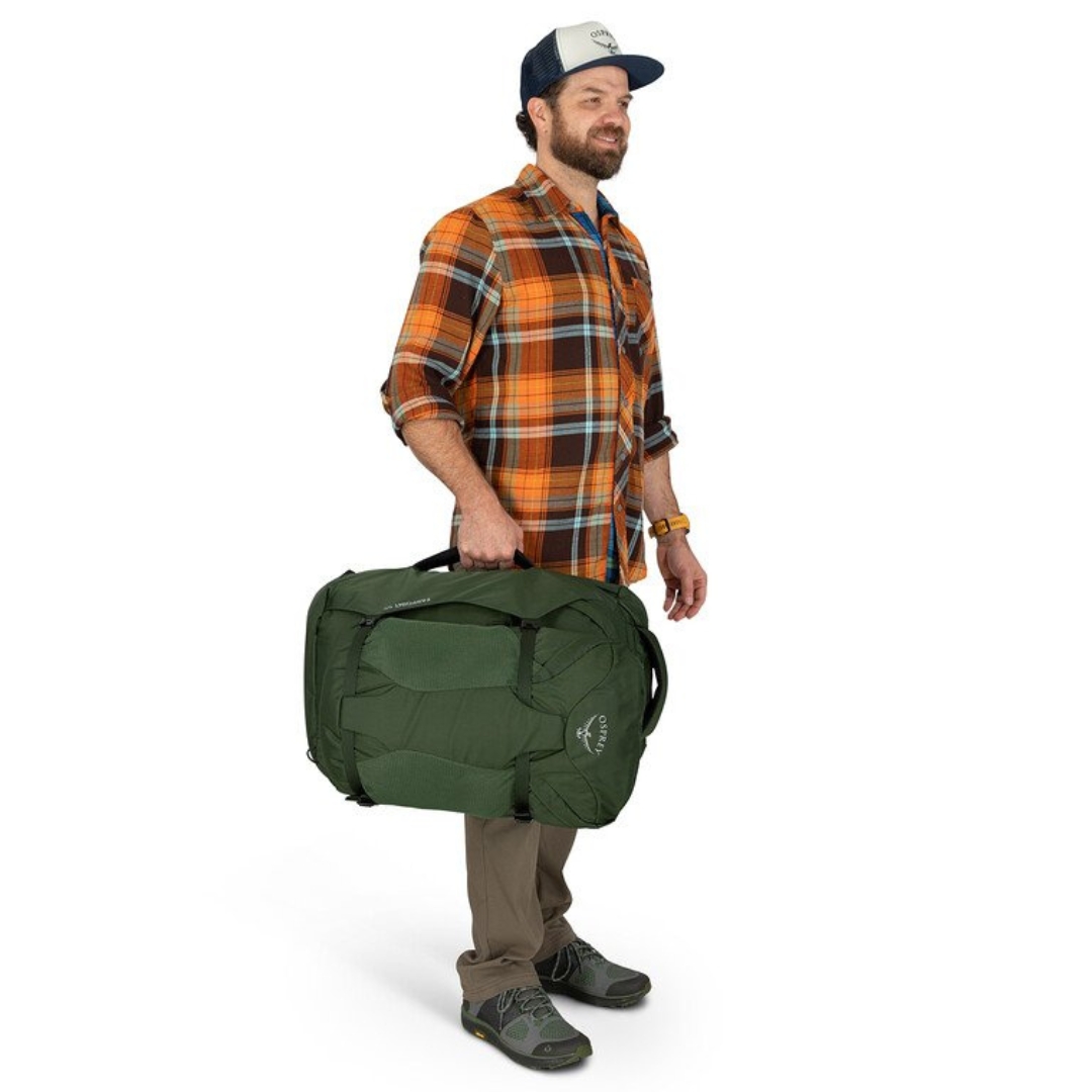 SAC DE VOYAGE OSPREY FARPOINT 55 POUR HOMME PORTÉ PAR UN HOMME VU AVEC LE SAC À LA MAIN