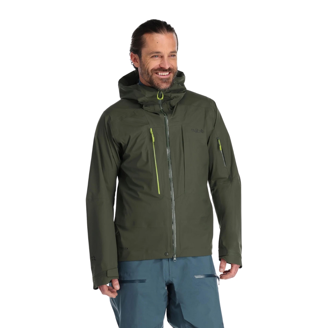 MANTEAU DE SKI RAB KHROMA KINETIC POUR HOMME COULEUR ARMY VU DU MANTEAU VERT OLIVE FONCÉ PORTÉ PAR UN HOMME VU DE LA TÊTE AUX CUISSES DE FACE