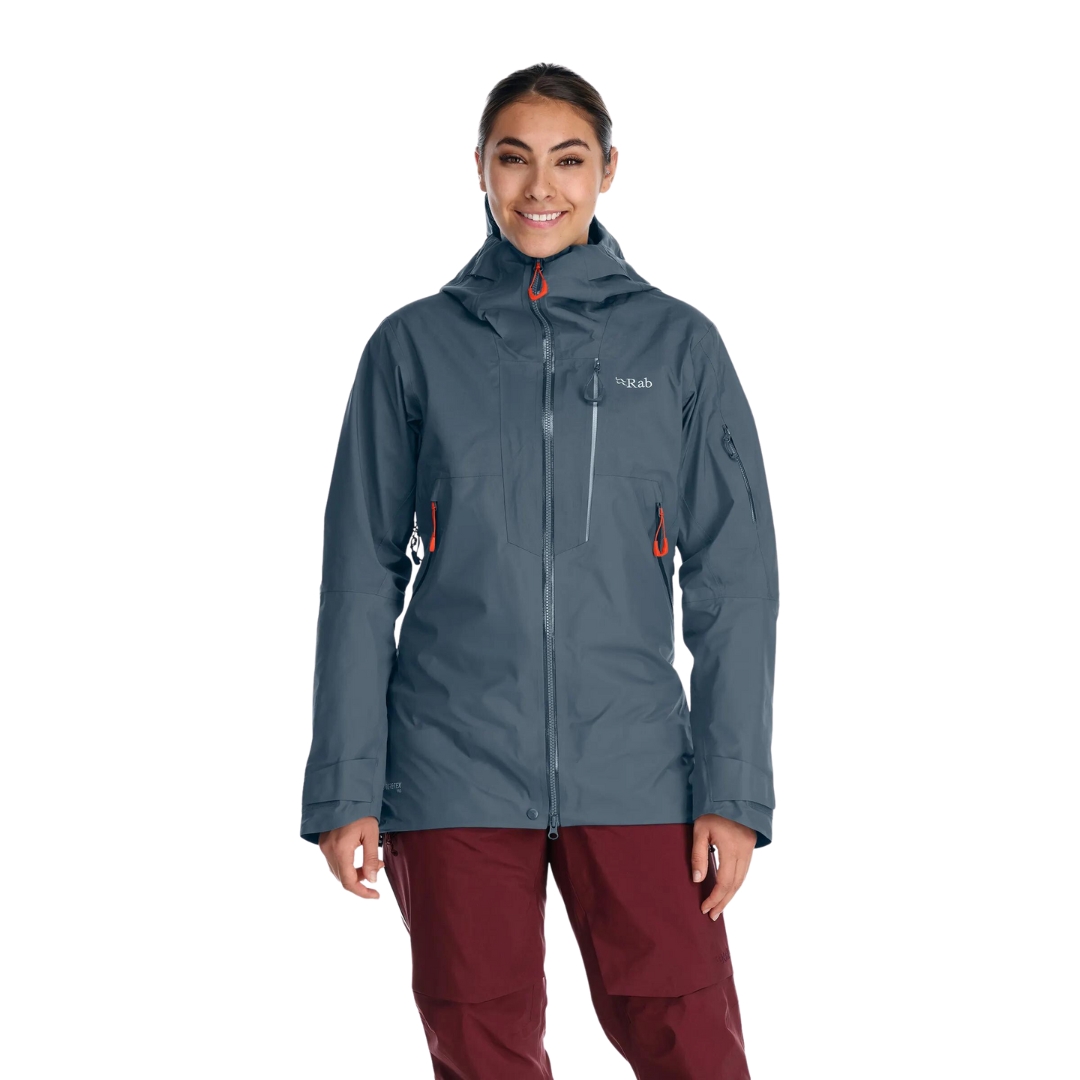 MANTEAU DE SKI RAB KHROMA LATOK GTX POUR FEMME COULEUR ORION BLUE VU DU MANTEAU BLEU ACIER PORTÉ PAR UNE FEMME VUE DE LA TÊTE AUX CUISSES DE FACE