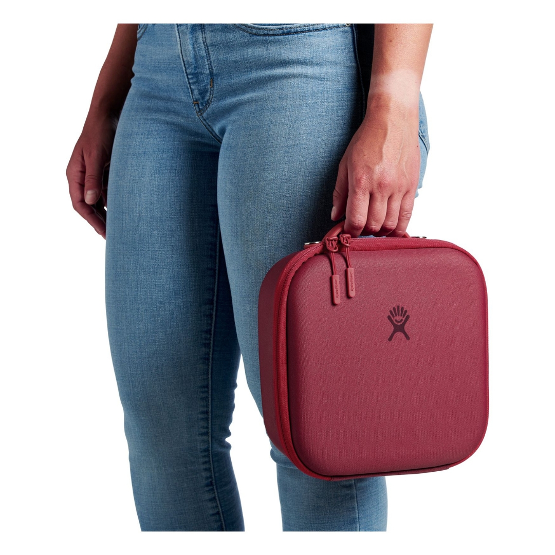 BOITE À LUNCH ISOTHERME HYDRO FLASK PETITE COULEUR BERRY VUE DE LA BOITE À LUNCH ROSE/ROUGE FONCÉ PORTÉE A LA MAIN PAR UNE FEMME