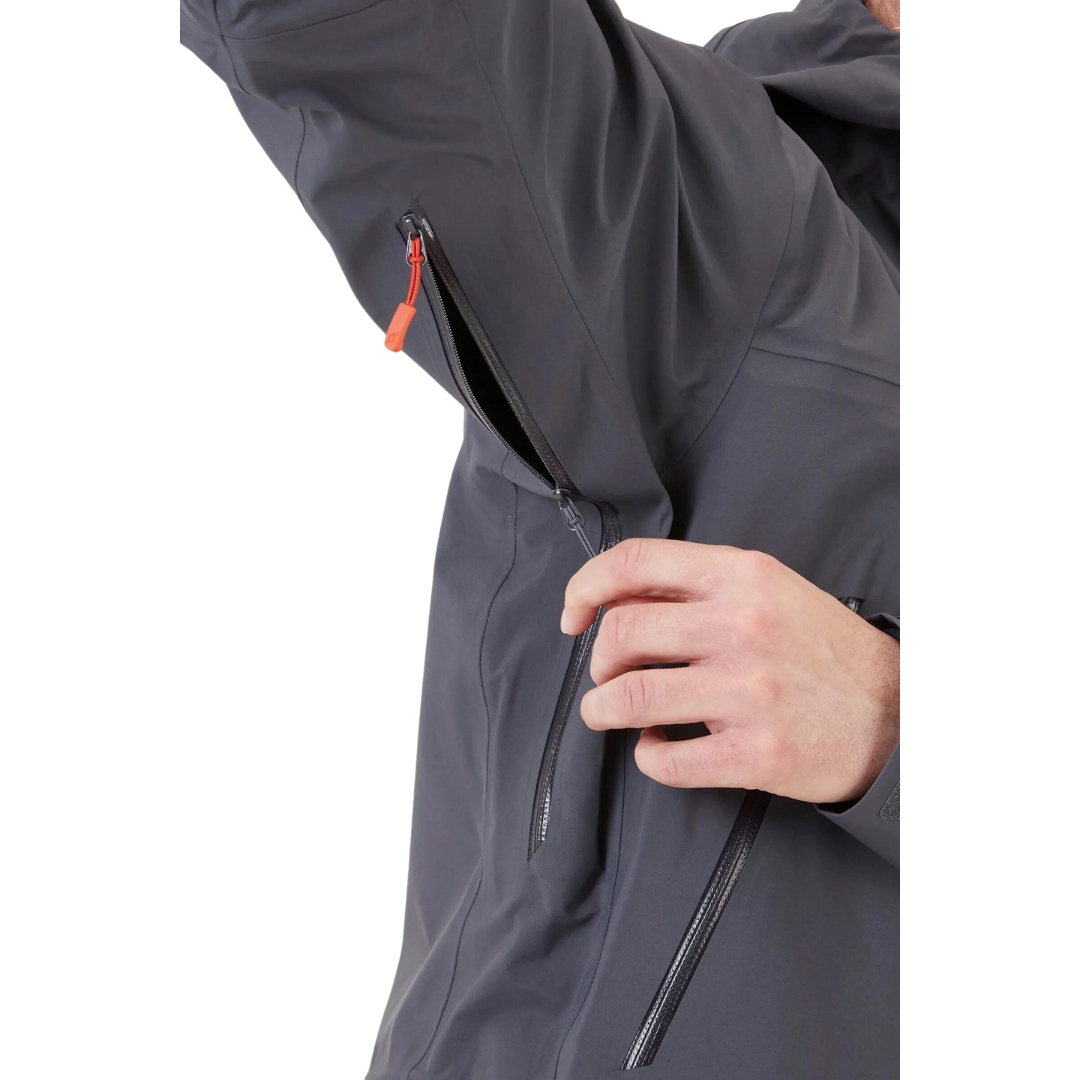 COQUILLE RAB KANGRI GORE-TEX POUR HOMME couleur graphene vu du manteau gris fonbcé et détails orange porté par un homme vu en gros plan sur les évents sous les aisselles